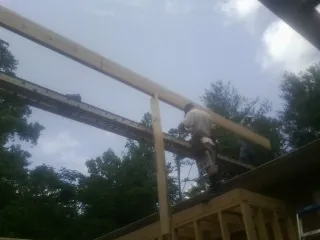 Carpenter setting a ridge beam over a new addition frame — Ice Dam Removal by Roofing Brothers in Hazlehurst