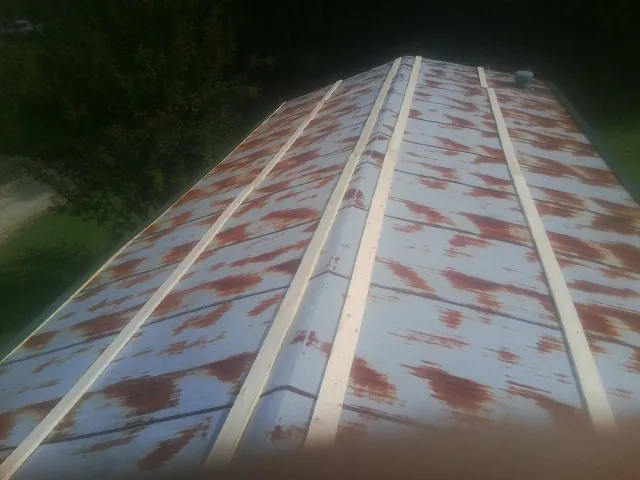 Rusted metal roof panels with new wood purlins before replacement in Hazlehurst