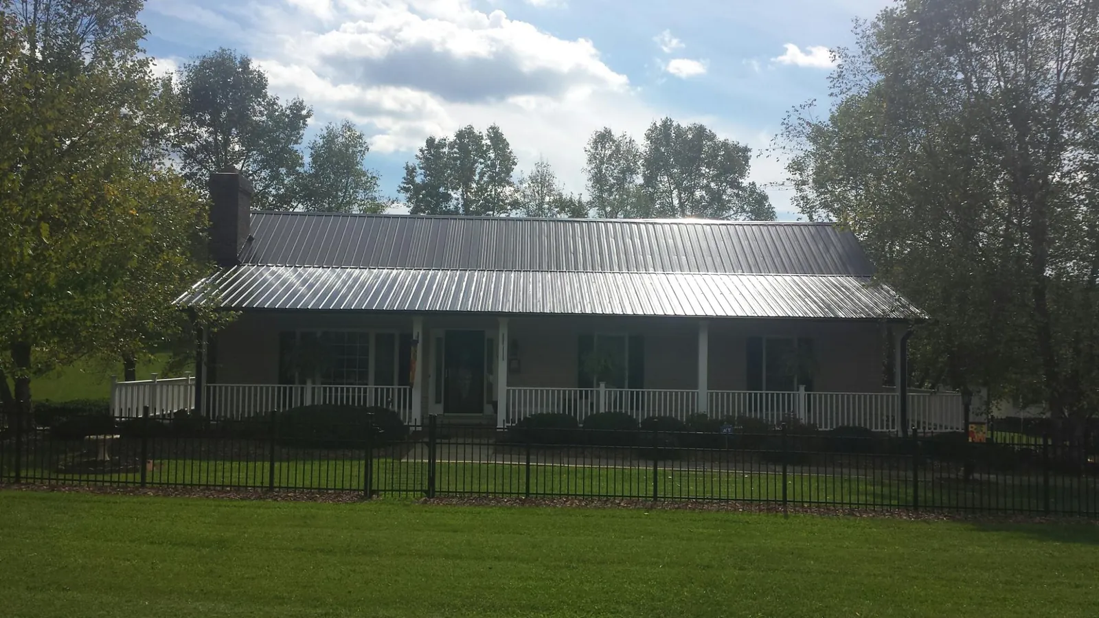 Gray metal roof on a brick ranch with a full width front porch — Gutter Guard Installation work by our crew in Hazlehurst